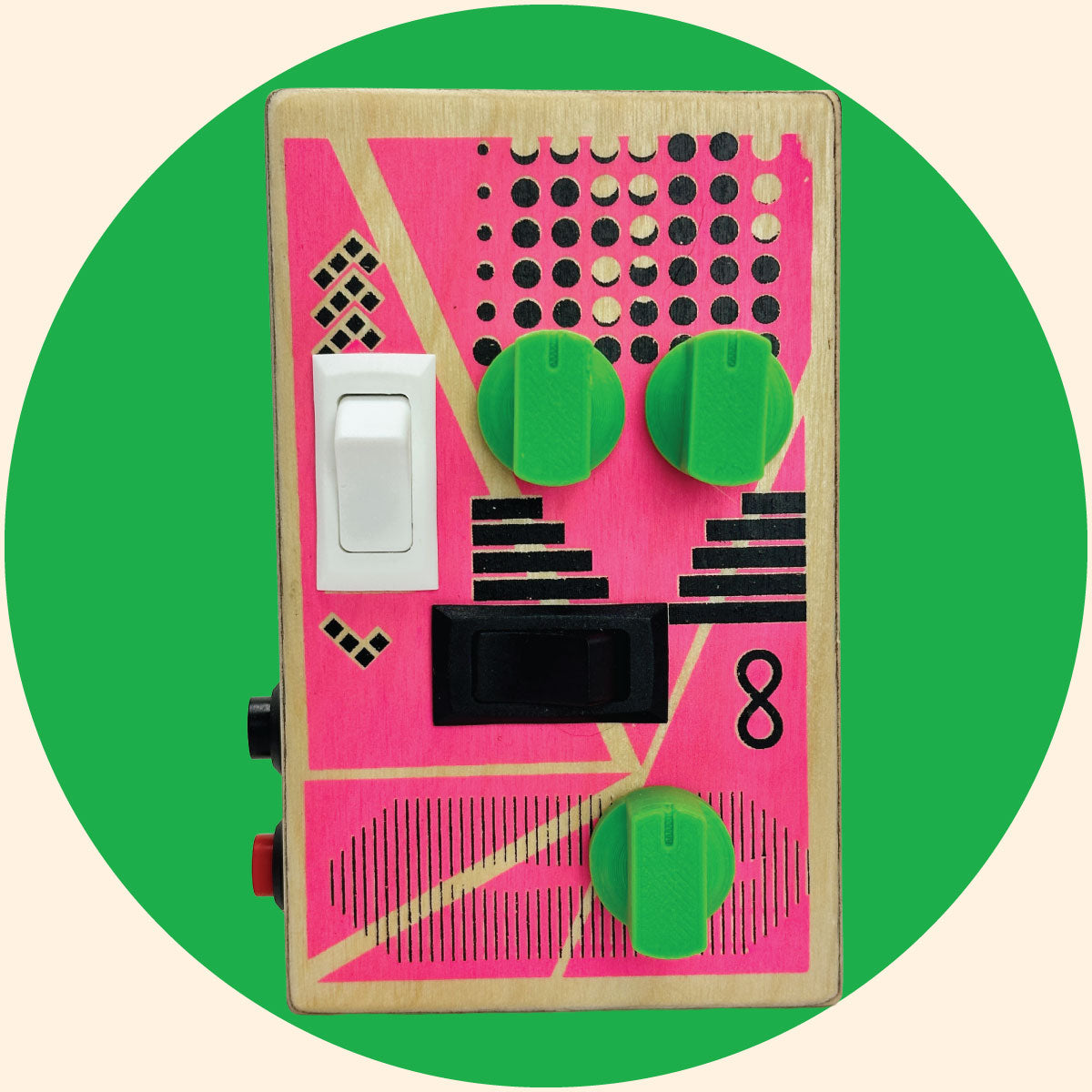 Pink and black graphic design on a baltic birch wood box. The sound device has green control knobs, white and black rocker switches